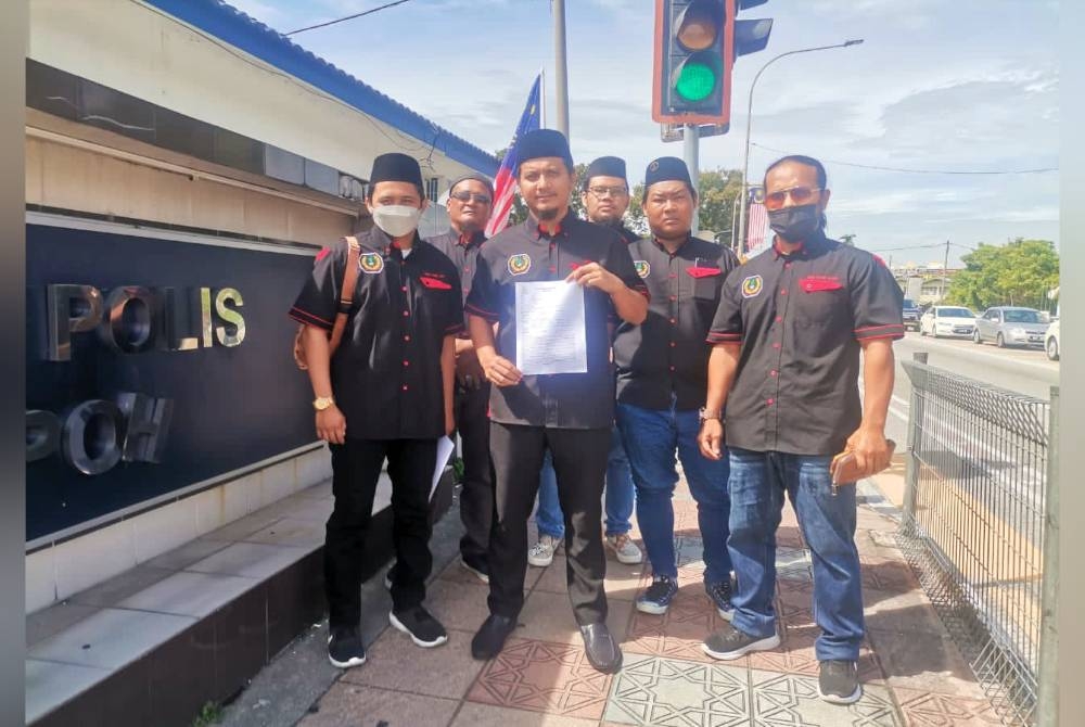 Mohd Amir (tengah) menunjukkan laporan polis yang dibuat di IPD Ipoh pada Jumaat.