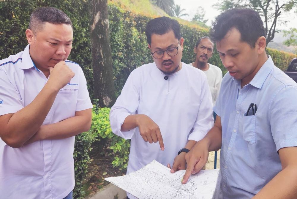 Harrison (tengah) mendengar taklimat diberikan wakil Nirwana Memorial Park Klang berhubung situasi banjir lumpur di Kampung Bukit Kapar Tambahan dan Jalan Seri Jaya di sini pada Jumaat.