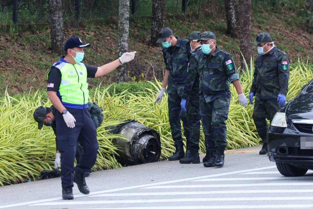 Anggota Polis Diraja Malaysia melihat serpihan bangkai pesawat yang bertaburan di sekitar Lebuhraya Guthrie berdekatan Bandar Elmina pada Jumaat. - Foto Bernama