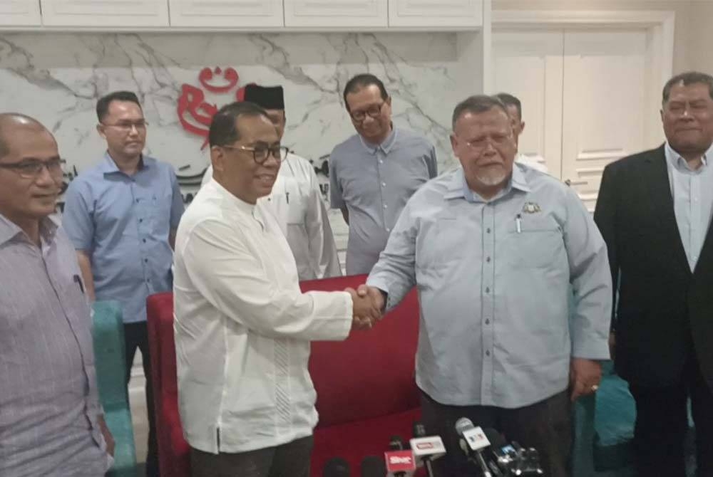 Mohamed Khaled (dua dari kiri) bersalaman dengan Aminolhuda (dua dari kanan) pada pertemuan kepimpinan BN dan PH di Ibu Pejabat UMNO Johor pada Jumaat.