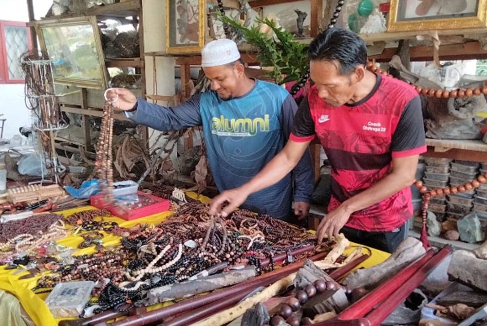 Ahmad Lokman (kiri) menunjukkan tasbih daripada kayu yang dihasilkan di Pusat Herba dan Kraf Melawi, 1001 Rahsia Khazanah Rimba pada Jumaat.