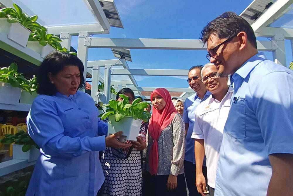 Saraswathy (kiri) melihat sayuran sawi putih yang ditanam di SMK Air Kuning menerusi program Kebun Nuri Nutrisi di bawah pelaksanaan inisiatif jangkauan komuniti Bank Rakyat.