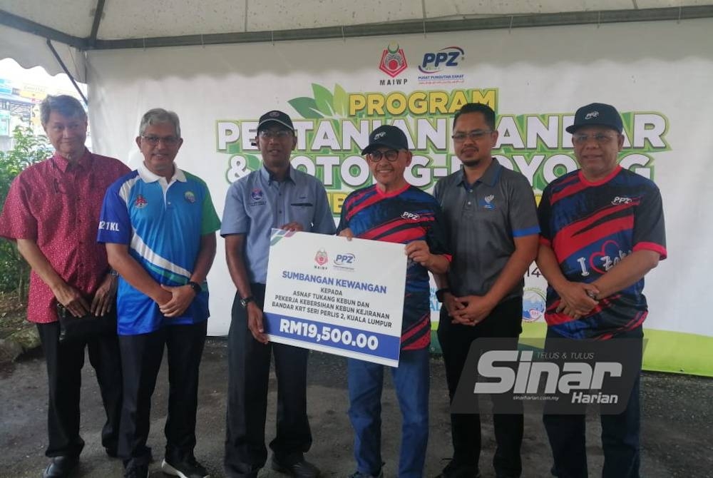 Abdul Aziz (tiga dari kanan) menyampaikan sumbangan kewangan bagi program pertanian bandar di Kebun Kejiranan Bandar KRT Seri Perlis Perlis 2 pada Sabtu.