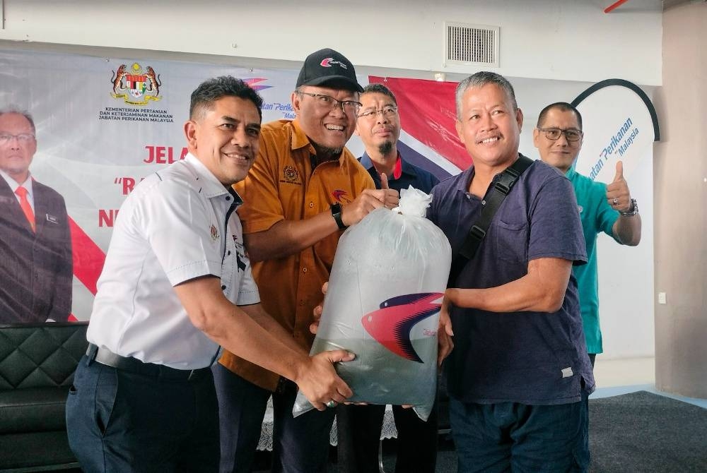 Abdullah (kiri) dan Adnan (tengah) menyerahkan 1,000 ekor benih ikan kepada penternak akuakultur.