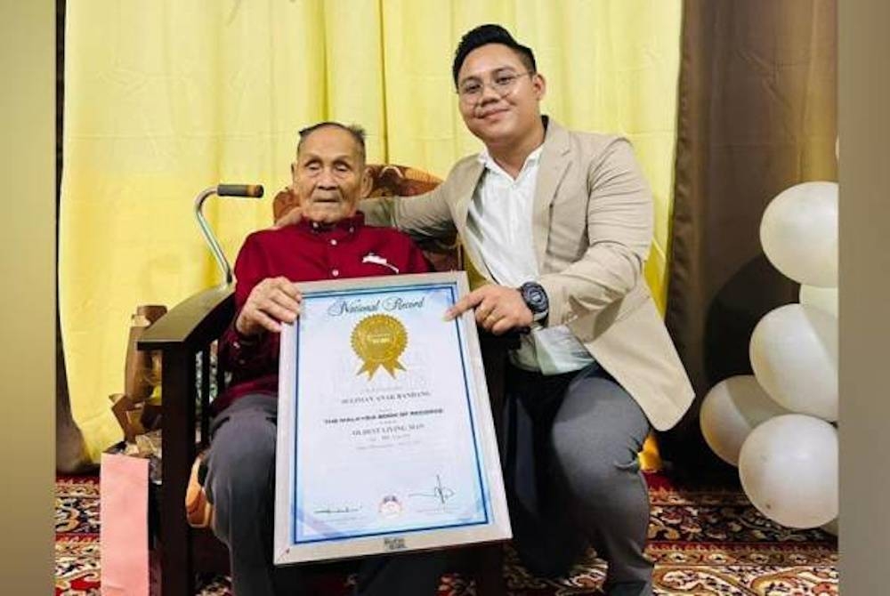 Seliman Bandang ketika meraikan ulang tahun kelahirannya ke -113 di Saratok bersama cucunya dengan memegang sijil Malaysia Book of Record sebagai lelaki tertua di Malaysia. - Foto Michael Bandang