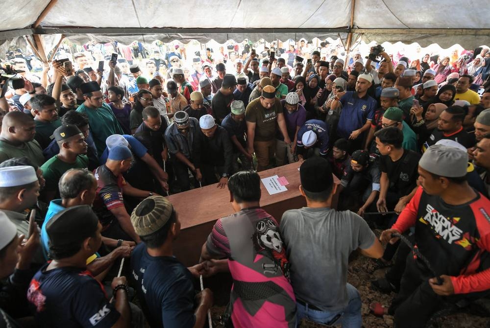 Jenazah penunggang p-hailing Allahyarham Muhamad Hafiz Muhamad Saleh, 32, diturunkan ke dalam liang lahad untuk pengkebumian di Tanah Perkuburan Islam Kampung Jerung, pada Sabtu. - Foto Bernama