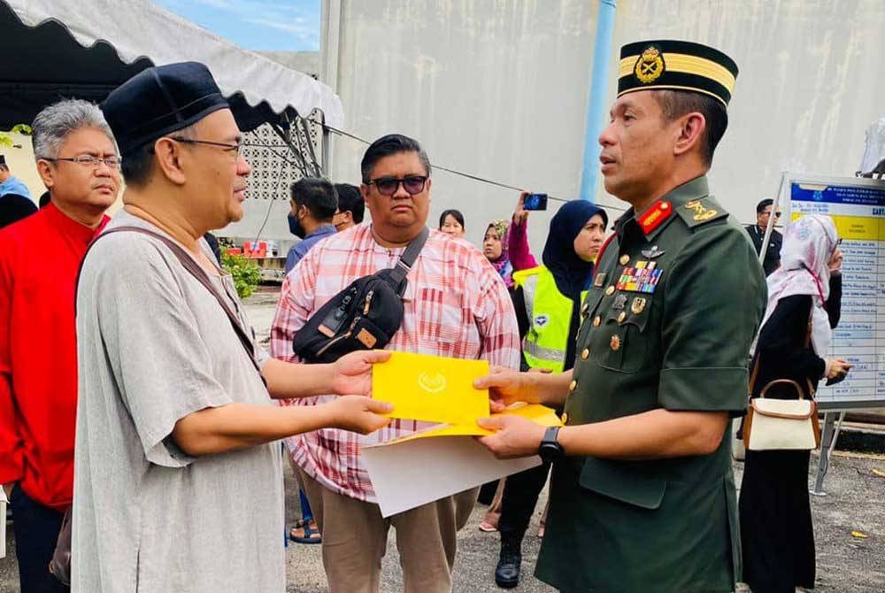 Zahari (kanan) menyampaikan sumbangan peribadi Agong kepada waris mangsa nahas pesawat terhempas di Lebuhraya Guthrie berdekatan Bandar Elmina di Shah Alam.