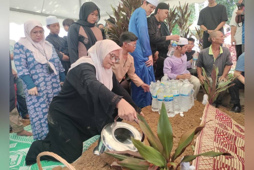 Adlina (kiri) menyiram pusara suaminya, Allahyarham Idris di Tanah Perkuburan Islam Barak dekat Benus, Bentong pada Ahad.