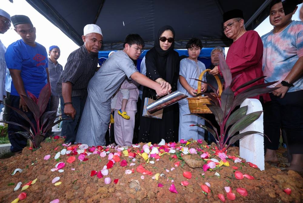 Balu Allahyarham Shahrul Kamal bersama anaknya menyiram air di atas pusara Allahyarham selepas selesai majlis pengebumian di Tanah Perkuburan Islam Klang Gate Hulu Klang hari ini. - Foto Bernama