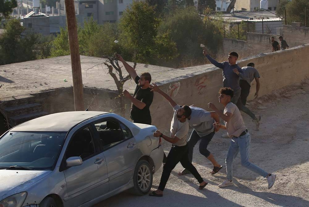 Penunjuk perasaan Palestin membaling batu ke arah tentera Israel semasa pertempuran berikutan serbuan Israel di kampung Beita berhampiran bandar Nablus di Tebing Barat. Foto Xinhua