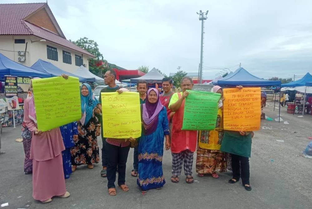 Sekumpulan peniaga memegang plakad membantah cadangan terhadap keputusan memindahkan mereka ke lokasi perniagaan lain.