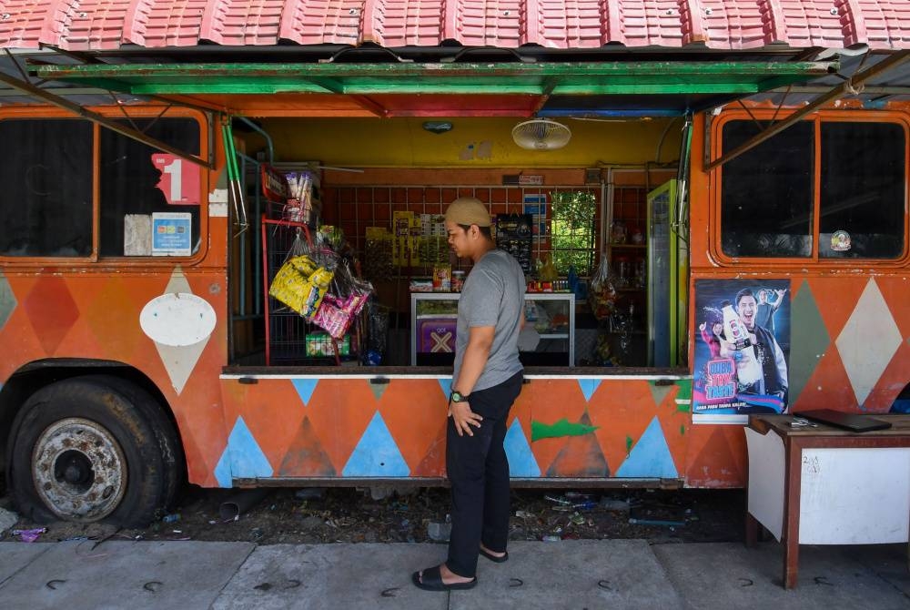 
Mohd Luqman Hakim menjalankan perniagaan kedai runcit di dalam sebuah bas yang telah diubai suai oleh bapanya di Kampung Tanjong Katong. - Foto Bernama