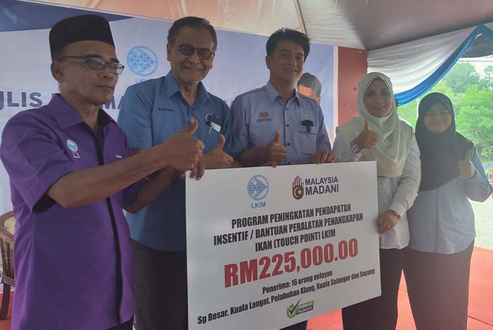 Muhammad Faiz (tiga dari kanan) menyampaikan replika cek bernilai RM225,000 bagi program peningkatan pendapatan nelayan kepada Pengerusi Persatuan Nelayan Negeri Selangor, Omar Abdul Rahman (kanan) pada Majlis Rahmah Mesra Madani bersama LKIM di Jeti Nelayan Sungai Buloh Jeram di sini pada Rabu.