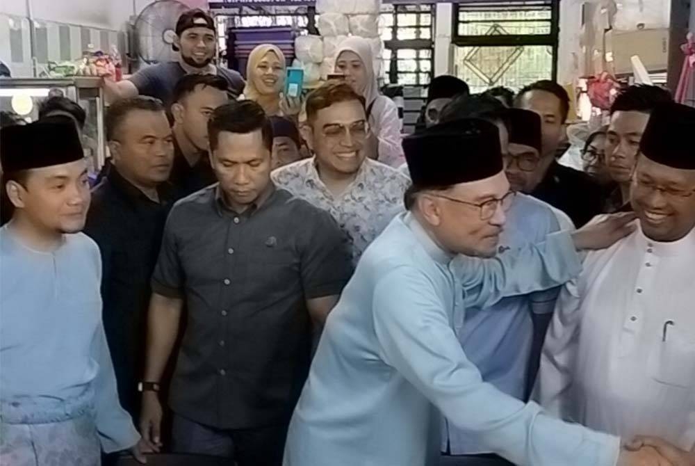 Anwar bersalaman dengan orang ramai di medan selera Taman Cempaka, Kempas diperhatikan Suhaizan (kanan).