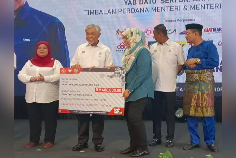 Ahmad Zahid (tengah) menyerahkan insentif kepada penerima dalam Majlis Perasmian Program Belia dan Desa Madani @KKDW di B5 Street Market, Tampoi, Johor Bahru pada Jumaat