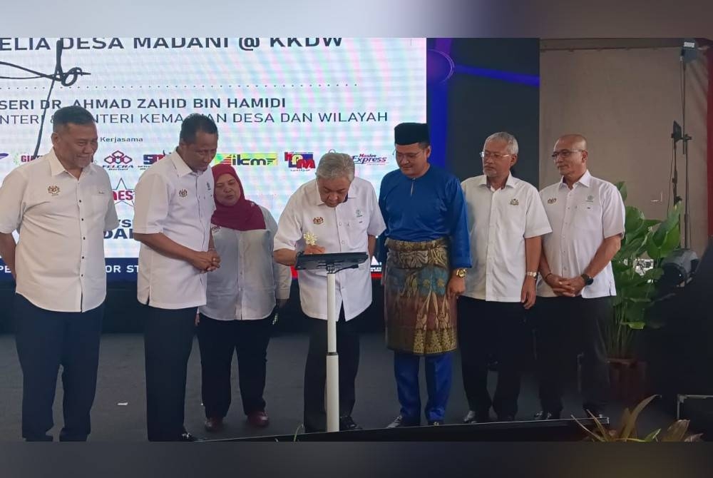 Ahmad Zahid (tengah) menurunkan tandatangan menyempurnakan Majlis Perasmian Program Belia dan Desa Madani @KKDW di B5 Street Market, Tampoi, Johor Bahru pada Jumaat.