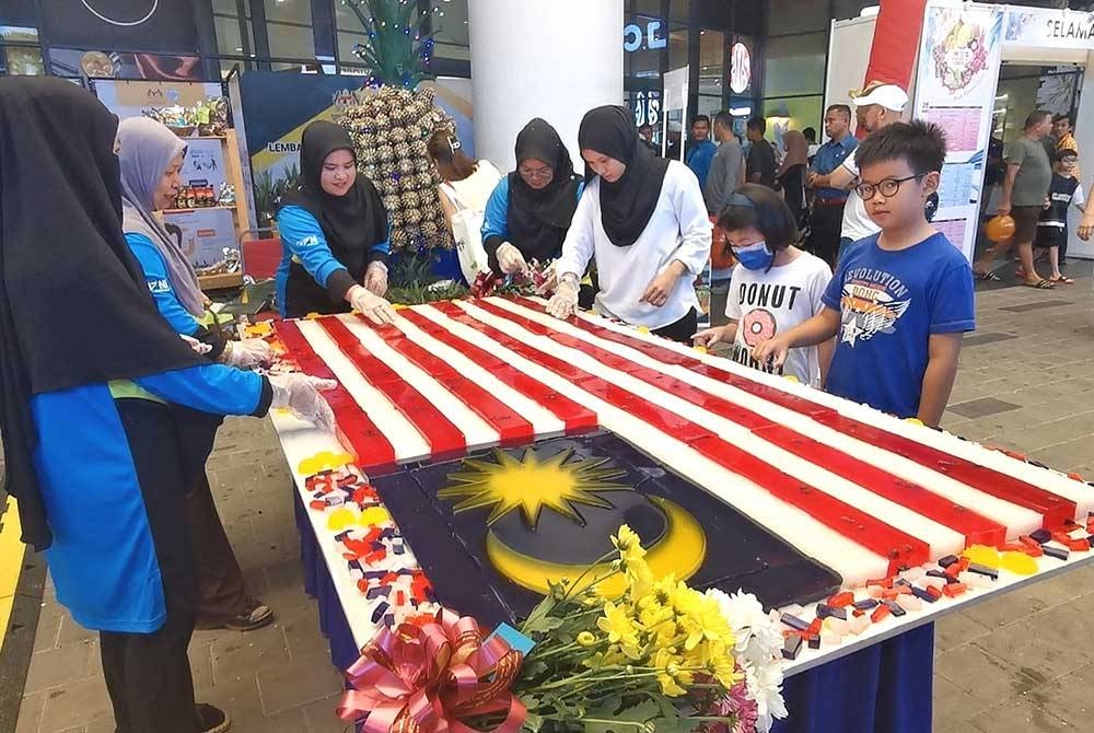 Mazni (dua dari kiri) dan kakitangan Quzni menyusun agar-agar Jalur Gemilang yang dipamerkan sempena Fama Fest Terengganu 2023 di Kuala Terengganu City Centre (KTCC Mall) pada Sabtu.