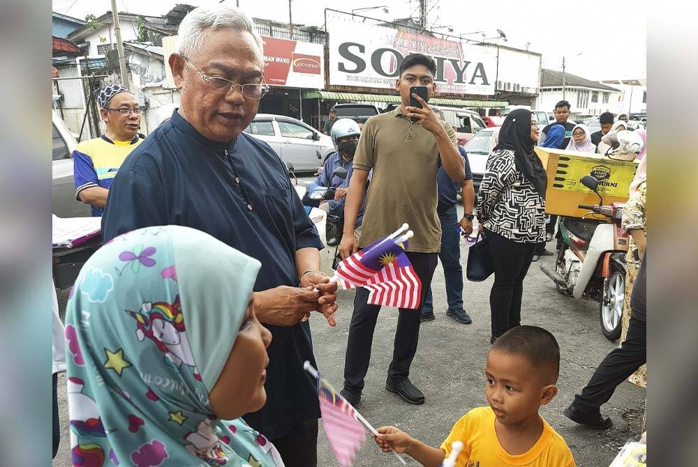 Noh mengedarkan Jalur Gemilang kepada pengunjung di tapak penjaja Pekan Tanjong Karang di sini pada Sabtu.