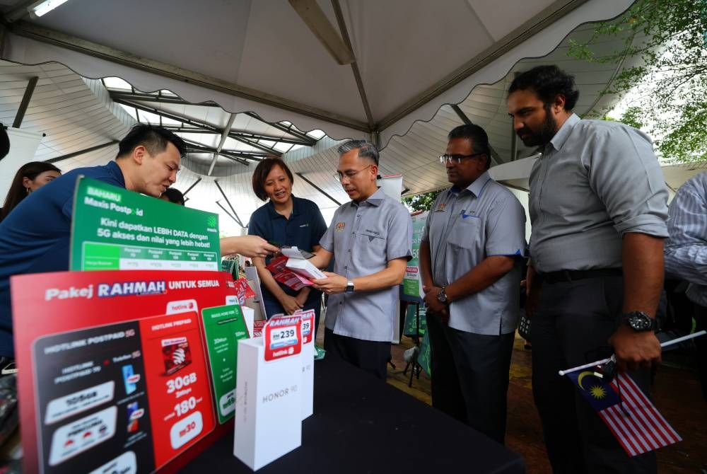 Fahmi (tiga dari kanan) melawat ke ruang jualan pada Pelancaran Pakej 5G Rahmah dan Insentif Pascabayar Rahmah Penjawat Awam di Anjung KKD hari ini. - Foto Bernama