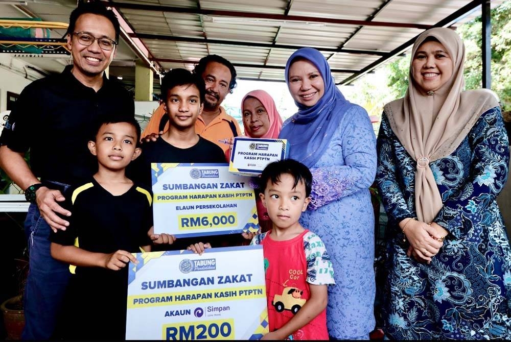 Norliza (dua dari kanan) menyerahkan sumbangan bantuan persekolahan dan simpanan dalam Simpan SSPN Prime kepada seorang pelajar yang telah dipilih sebagai anak angkat PTPTN di bawah Skim Anak Angkat YPM.