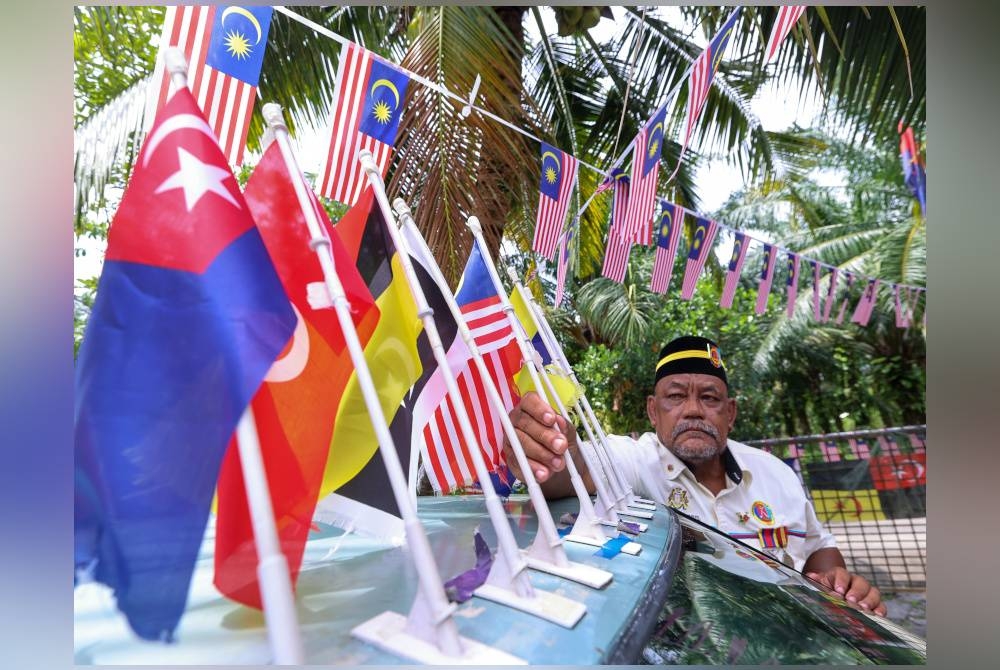 Fatahalmubil memasang lebih 200 Jalur Gemilang pada Proton Iswara dan kediamannya di Kampung Parit Keroma Laut. - Foto Bernama