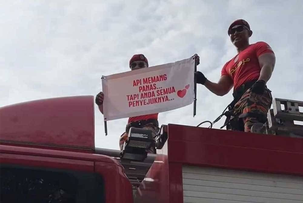 Aksi anggota bomba menyertai perarakan di Dataran Putrajaya membawa sepanduk pick-up line tertera ayat &#039;Api memang panas tapi anda semua penyejuknya&#039;. - Foto tular media sosial