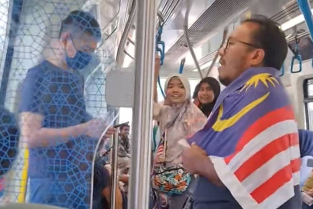 Tangkap layar video TikTok menunjukkan seorang lelaki dengan Jalur Gemilang menyanyikan lagu &#039;Tanggal 31&#039; sebelum diikuti oleh pengguna MRT yang lain