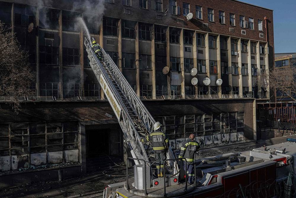 Anggota bomba bertugas memadamkan kebakaran bangunan di Johannesburg pada Khamis. - Foto AFP