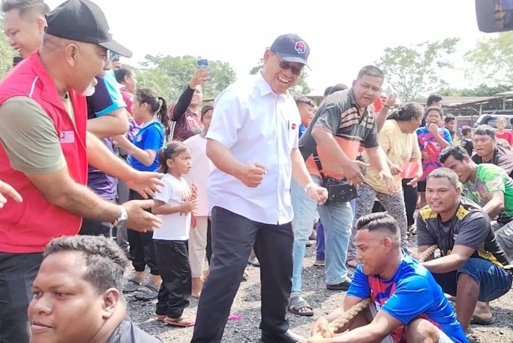 Suhaizan berdiri (tengah), memberikan kata-kata semangat kepada peserta acara tarik tali sempena Sukan Rakyat berkenaan.