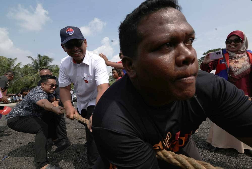 Suhaizan (tengah) menyertai sukan tarik tali bersama masyarakat Orang Asli Seletar pada Program Sukan Rakyat Orang Asli di Kampung Sungai Temun pada Jumaat. - Foto Bernama