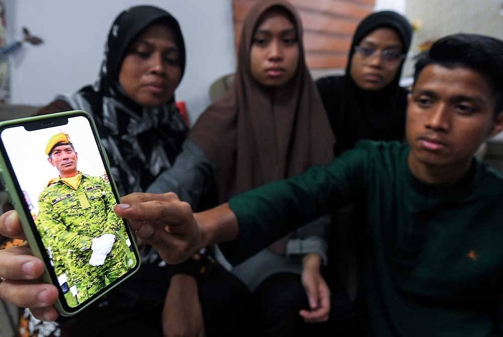 Maniliza Abdul Hamid, 47, (kiri) bersama anaknya Qistina Amierah, 21, Qistina Umairah, 18, dan Ahmad Harraz, 20, menunjukkan gambar terakhir Allahyarham Muhammad Noh Muhammad Isa di kediamannya di Kampung Bahagia Jiboi, Ampangan. - Foto Bernama.