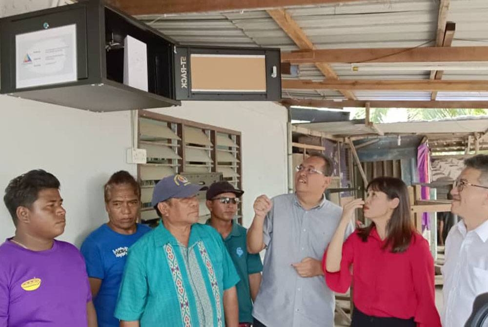 Nie Ching (dua dari kanan), Chin Tong (kanan) dan penduduk setempat melawat tapak pemasangan peranti satelit Starlink di Dewan Kampung Orang Asli Sungai Temon, Johor Bahru pada Sabtu.