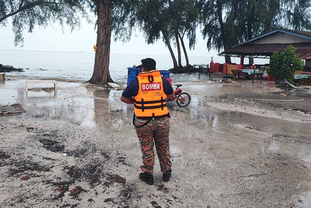 Anggota bomba memantau fenomena air pasang besar yang melimpah di Pantai Remis, pada Sabtu.