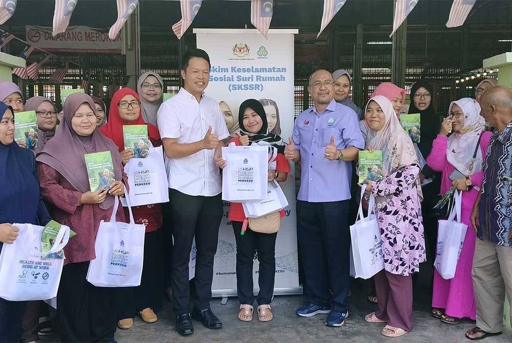 Hisham (depan, lima dari kanan) dan Chun Kuang ( depan, empat dari kiri) bersama sebahagian suri rumah yang menerima tajaan SKSSR DUN Semambu pada majlis penyerahan nota perlindungan skim itu di Cenderawasih pada Ahad.