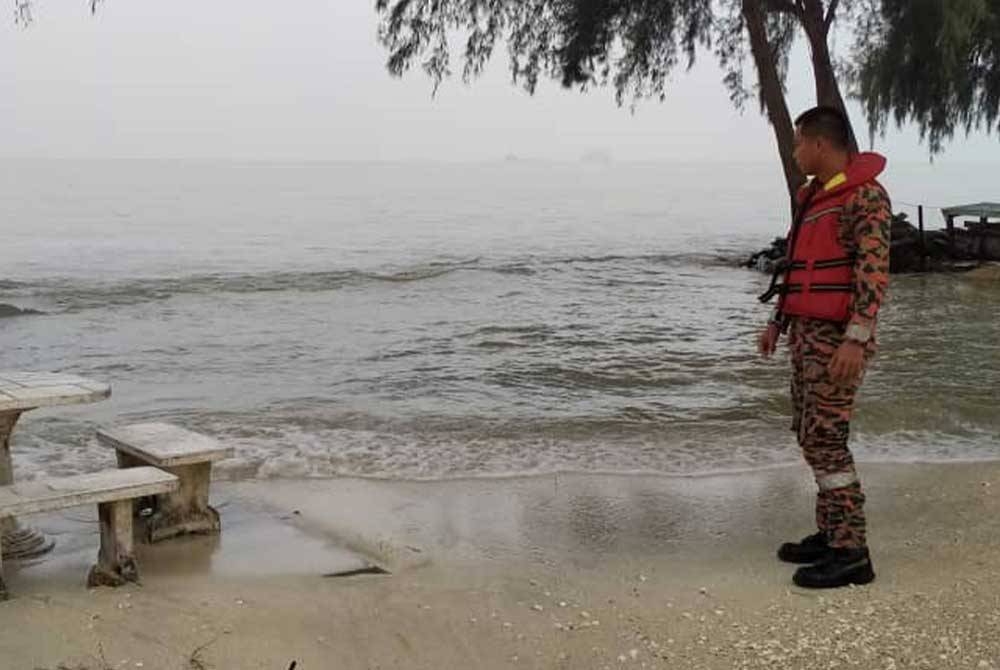 Anggota bomba memantau fenomena air pasang besar di Pantai Remis Jeram pada Ahad.