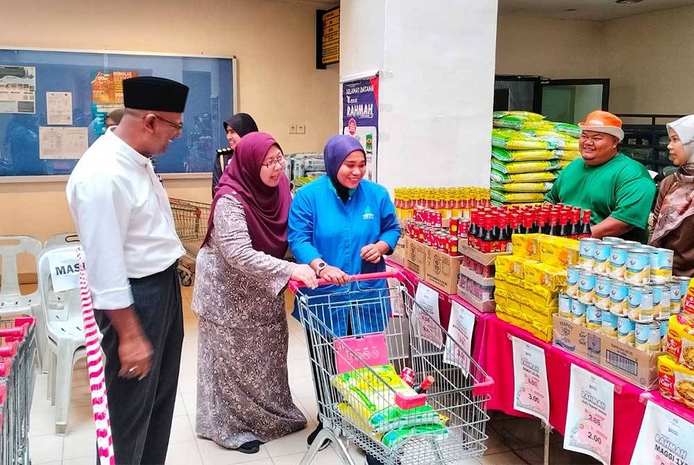 Fuziah (dua dari kanan) membantu pengunjung Program Jualan Rahmah di Kompleks Pentadbiran Kerajaan Persekutuan Anak Bukit membeli barangan keperluan.