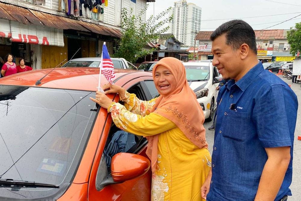 Dr Hafidzah (kiri) dan Muhd Nor Aswadi menjayakan Program Komunikasi Tindakan Setempat dan Sambutan Hari Kebangsaan di Pasar Kubang Pasu, Kota Bharu pada Isnin.