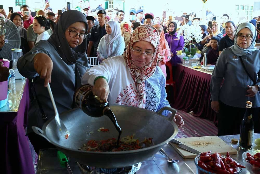 Tunku Azizah berkenan memasak sambal ikan bilis berlada sewaktu tiba pada program Santapan Rakyat di Dewan Perdana hari ini. - Foto Bernama