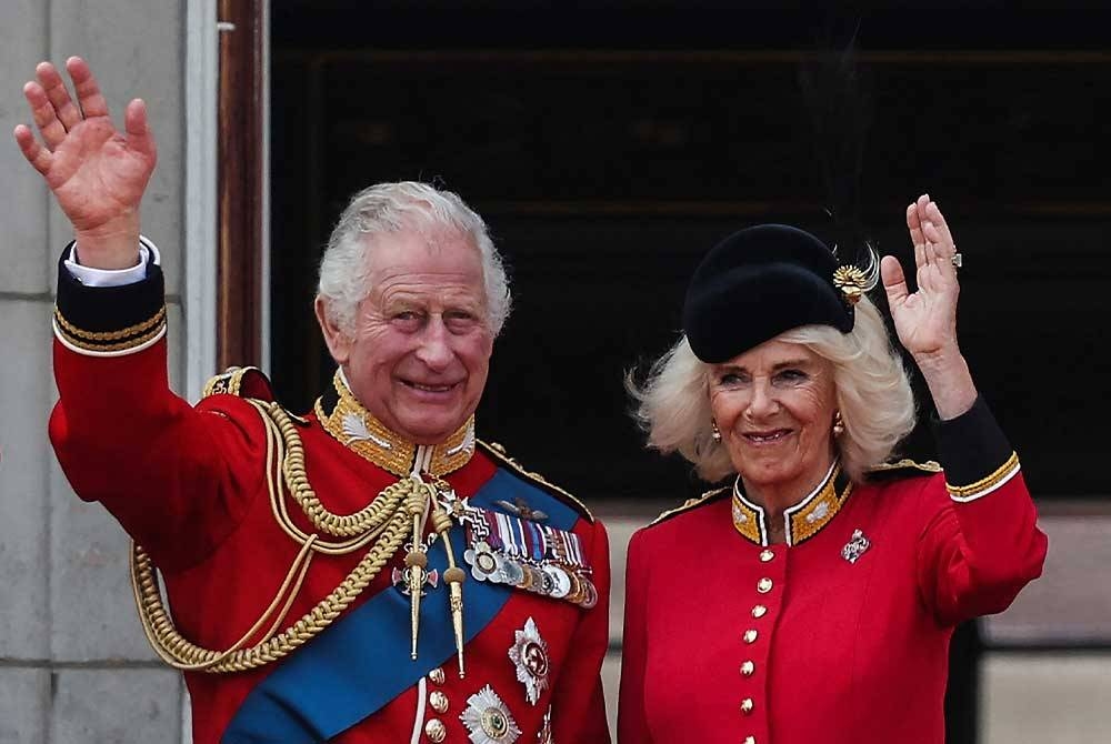 Raja Charles III dan Ratu Camilla melambai di balkoni Istana Buckingham. - Foto AFP