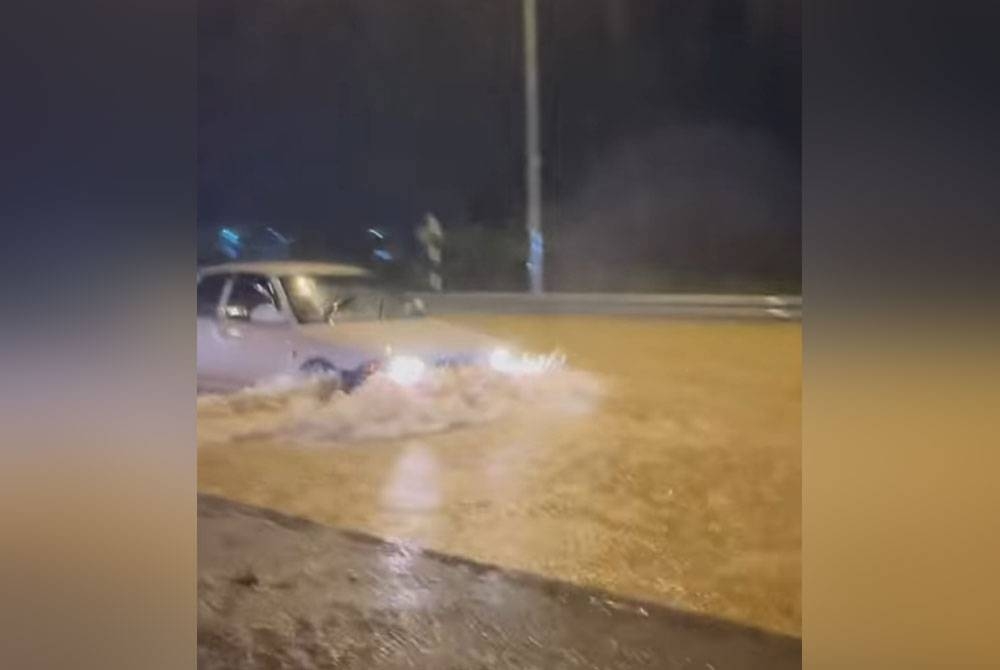 Tangkap layar menunjukkan sebuah kereta meredah banjir di Jalan Persiaran Puncak Alam 6 berdekatan sebuah pusat servis kereta pada Selasa.