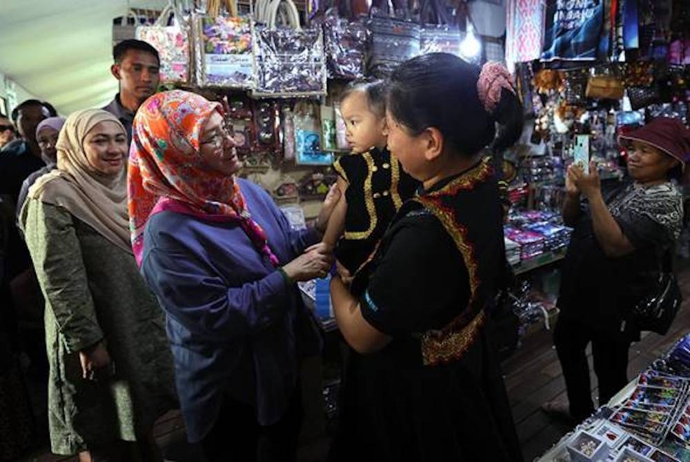 Raja Permaisuri Agong, Tunku Azizah Aminah Maimunah Iskandariah berkenan menyantuni para peniaga dan masyarakat setempat ketika membuat lawatan ke Pekan Nabalu Pekan Nabalu sempena Kembara Kenali Borneo hari ini. - Foto Bernama