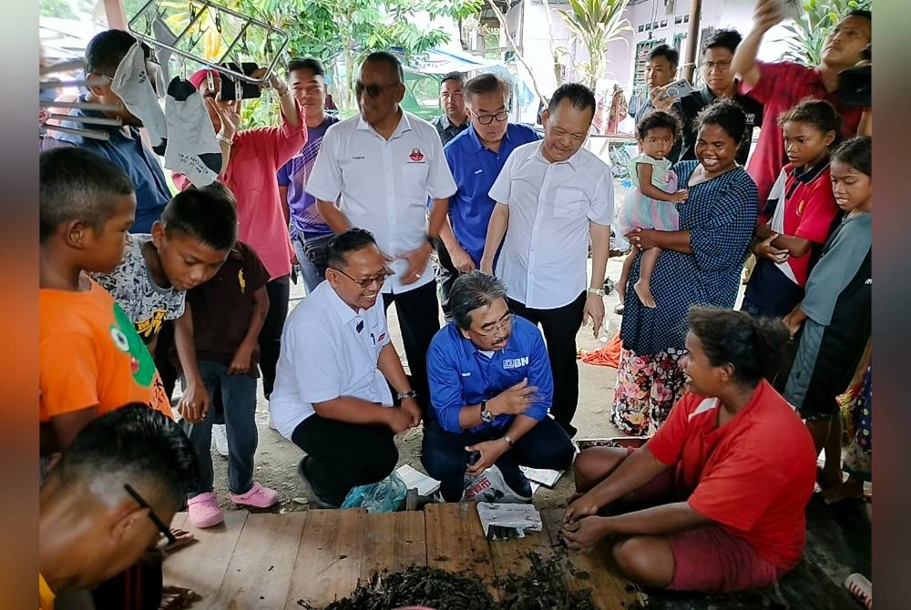 Suhaizan (tengah) melihat penduduk Kampung Bakar Batu membersihkan hasil laut untuk dijual.