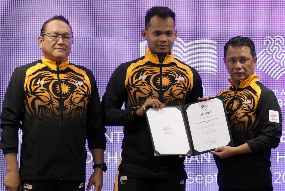 Mohamad Norza menyerahkan watikah Shah Firdaus selaku pembawa Jalur Gemilang pada Majlis Penyerahan Watikah Pemilihan Kontinjen Malaysia ke Temasya Sukan Asia ke-19 Hangzhou hari ini. Foto Bernama