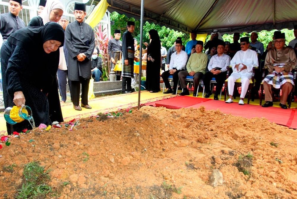 Datin Seri Che Ezatul Hamsiah Hussein, 77, (kiri) menyiram air di pusara suaminya, yang juga bekas Timbalan Menteri Pertahanan Allahyarham Datuk Seri Dr Abdullah Fadzil Che Wan di Tanah Perkuburan Masjid Panglima Kinta pada Rabu. - Foto Bernama