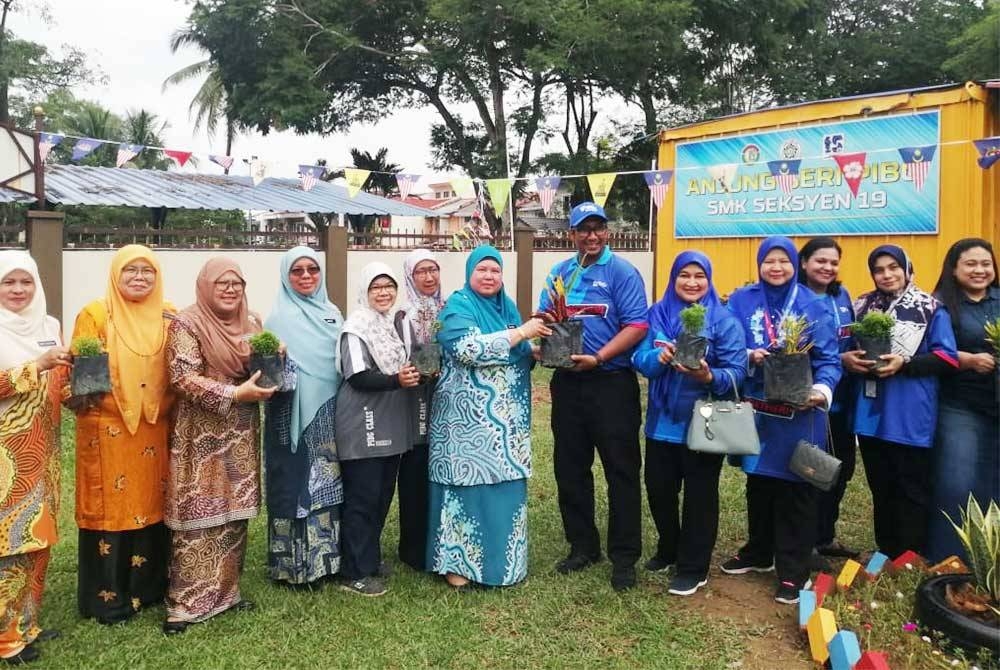 Gimik penyerahan sumbangan pokok hiasan disampaikan oleh Mohd Affendi kepada Rohana (tujuh dari kiri).