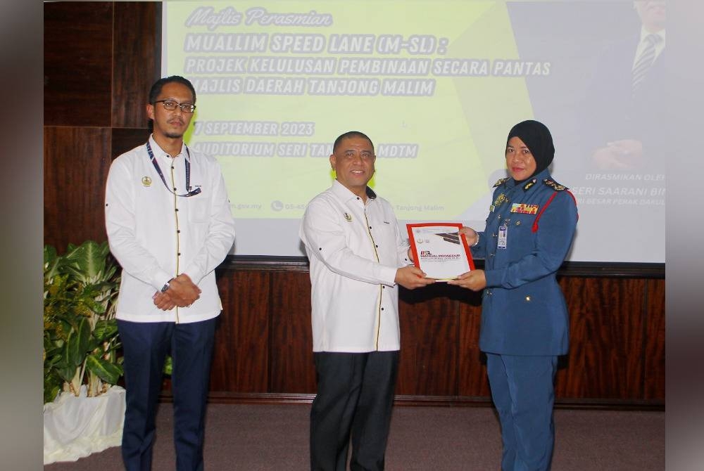 Saarani (tengah) menyampaikan buku Manual Prosedur M-SL kepada Pengarah Jabatan Bomba dan Penyelamat Malaysia (JBPM) Perak, Sayani Saidon (kanan) pada perasmian M-SL: Projek Kelulusan Pembinaan Secara Pantas di MDTM pada Khamis.