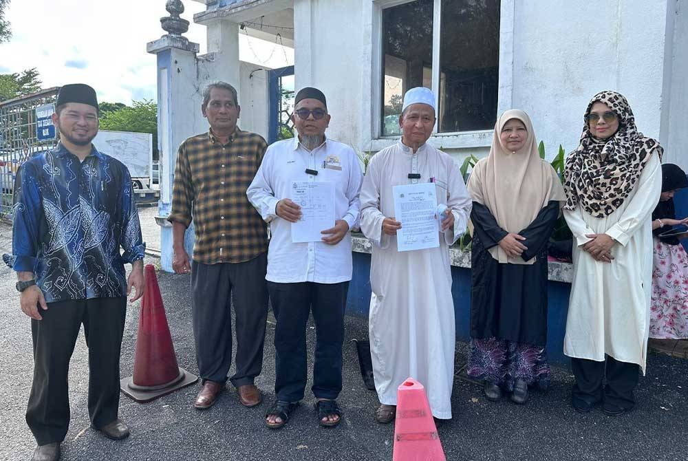 Manolito (tiga dari kanan) dan Mohd Azlan (tiga dari kiri) menunjukkan laporan polis yang dibuat di IPD Taiping pada Khamis.