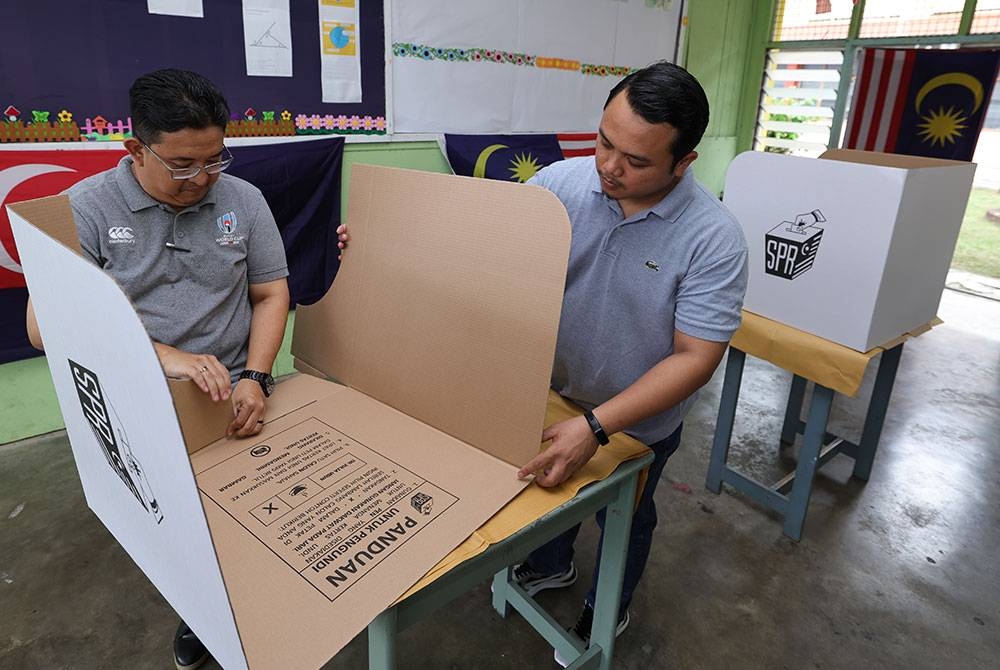 Petugas SPR, Nur Firdaus Mohamad Yusof, 45, dan Mohamad Asri Abd Samat, 31, (kanan) melakukan persiapan menjelang Pilihan Raya Kecil (PRK) Parlimen Pulai di Sekolah Menengah Kebangsaan Aminuddin Baki, pada Jumaat. - Foto Bernama