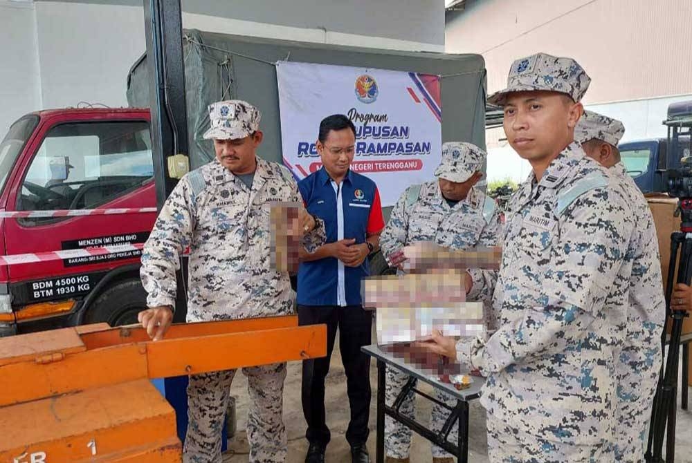 Mohd Khairulanuar (kiri) melupuskan rokok seludup yang dirampas.