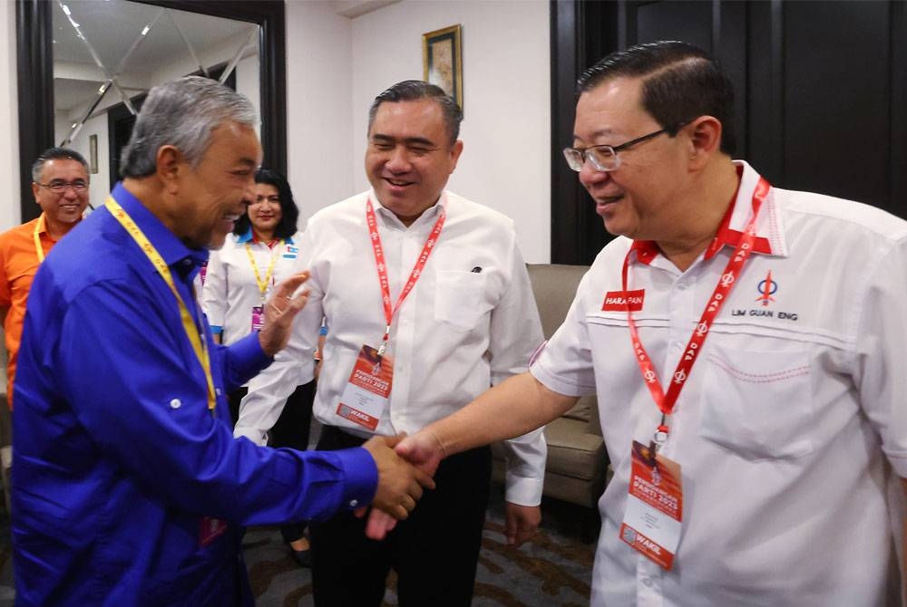 Guan Eng (kanan) bersalaman dengan Ahmad Zahid sambil disaksikan Menteri Pengangkutan yang juga Setiausaha Agung DAP, Anthony Loke (tengah) pada Persidangan Parti DAP 2023 di sebuah hotel pada Ahad. - Foto Bernama